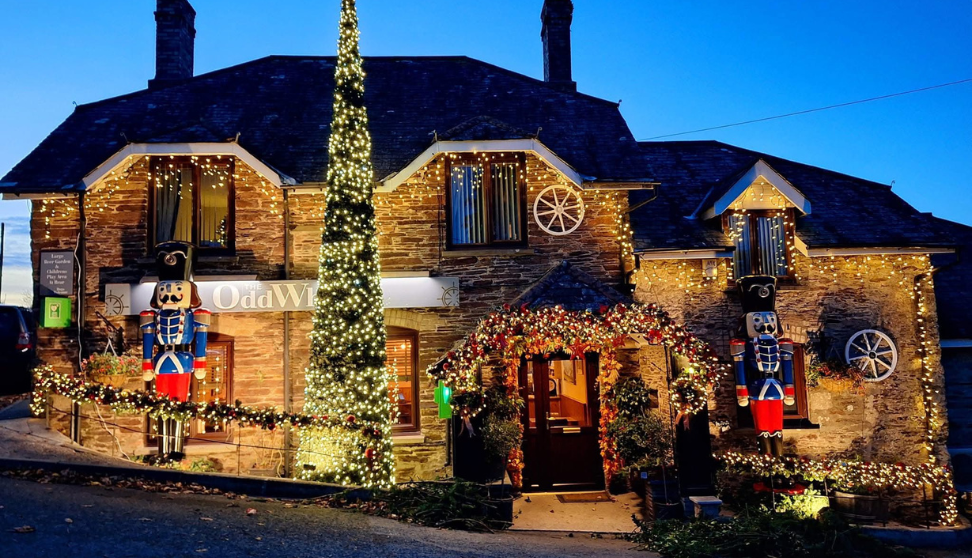 Festively lit stone pub decorated with nutcracker figures, twinkling lights, and a tall Christmas tree outside.